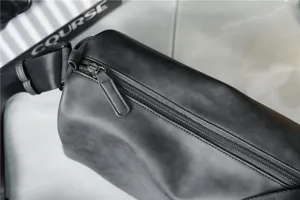 Close-up of men's cylindrical crossbody bag in dark gray PU leather with zipper detail.