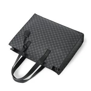Detail view of black PU leather tote bag with monogram pattern and double top handles.