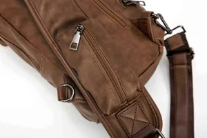 Detail view of brown leather chest bag zipper and strap craftsmanship, durable casual sling bag.