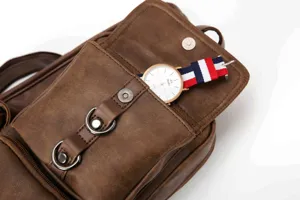 Detailed view of brown leather chest bag with front pocket, metal hardware, and zipper.