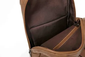Detail view of men's leather chest bag interior, showcasing lining and zipper pocket.