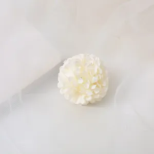 Close-up detail of a white artificial flower hair clip, featuring delicate fabric petals.