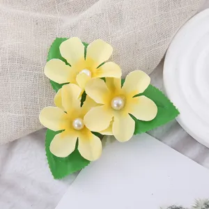 Detailaufnahme der hübschen gelben künstlichen Blumenhaarnadel mit Perlen und grünen Blättern.
