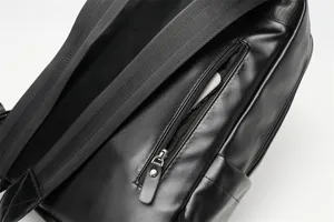 Primo piano dettagliato di zaino in pelle nera con tracolla diagonale e tasca con zip.