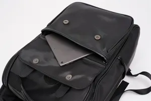 Black backpack front detail showing magnetic snap pocket and padded compartment for tablet device.