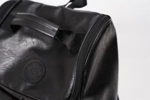 Primo piano dettagliato dello zaino retro in pelle nera, che mostra maniglia e zip di qualita.