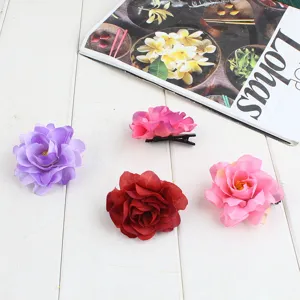 Gedetailleerd overzicht van gekleurde stoffen bloem haarspelden op wit hout, boho stijl.