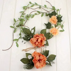 Detail view of bohemian artificial peony flower garland and belt set with green ivy leaves.