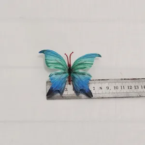 Vista dettagliata del fermaglio per capelli a farfalla in tessuto blu verde con design 3D.