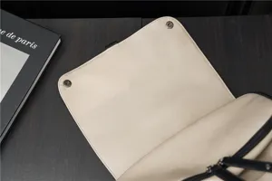 Vista dettagliata della patta dello zaino in pelle beige con chiusura a bottone magnetico.