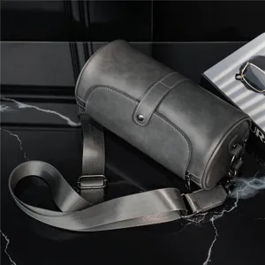 Detail view of a vintage gray cylindrical barrel shoulder bag with an adjustable strap.