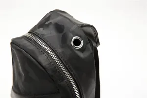 Close-up detail of a black camo sling chest bag featuring durable zipper and metal eyelet.