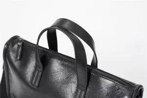 Primo piano dettaglio del manico in pelle nera per borsa ventiquattrore uomo con cerniera.