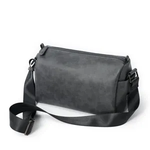 Detail view of a stylish grey cylinder crossbody bag with black adjustable strap for men.