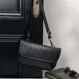 Detailed shot of a black woven leather crossbody bag with adjustable strap and metal hardware.