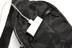 Detail shot of the black camouflage chest bag, showcasing zipper pocket and USB port design.