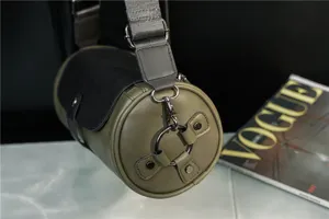Vintage cylinder shoulder bag for women and men, retro green crossbody bag with wide strap.