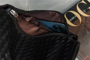 Close-up of black woven leather shoulder bag showing zipper pocket and interior capacity details.