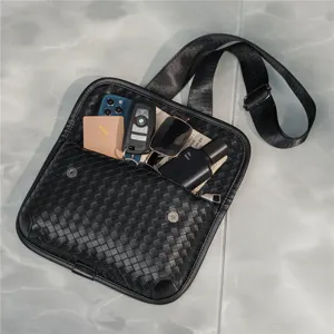Detailed view of black woven chest bag, showing interior capacity with stylish daily items.