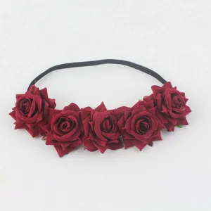 Close-up of dark red velvet rose headband detail showing five artificial flower charms.
