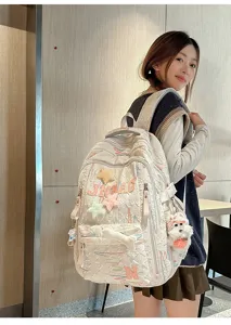 Detail shot of a casual quilted backpack with cute star patches and plush charm worn by model.