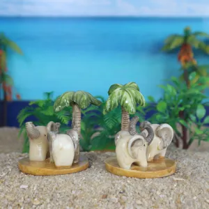 Primo piano dettagliato di statuette di elefanti e palme su sabbia, decorazione per piante.