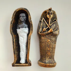 Egyptian pharaoh mummy sarcophagus detail showing open coffin with resin figure and hieroglyphs.
