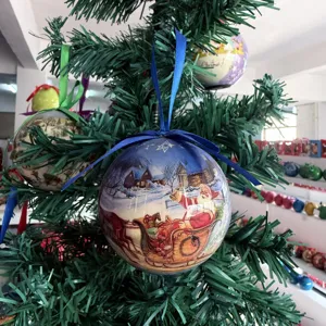 Nahaufnahme einer dekorativen Christbaumkugel, die an einem künstlichen Tannenbaum hängt.