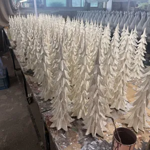 Detailed view of white distressed resin Christmas tree ornaments arranged in batch production.