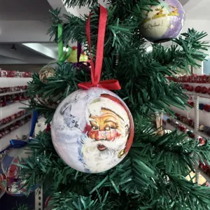 Nahaufnahme Detail von Vintage Weihnachtsmann Christbaumkugel an grünem Tannenzweig.