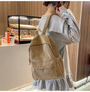 Detail view of the casual corduroy backpack worn by a model in a cozy cafe setting.