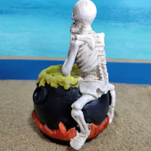 Detailed closeup view of Halloween resin skeleton sitting on a magic cauldron figurine.