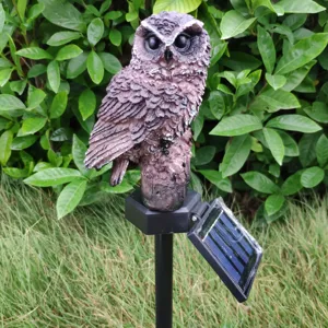 Close-up detail of outdoor solar owl garden stake light with solar panel and natural background.