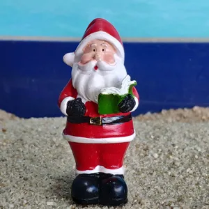 Close-up detail of a cute resin Santa Claus figurine holding a book, perfect for holiday decor.