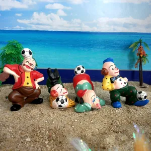 Detailed shot of four colorful clown figurines playing with soccer balls on sand for sandplay therapy.