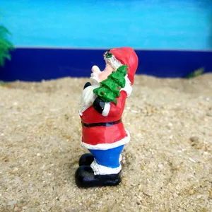 Detailed shot of miniature resin Santa Claus figurine holding a small tree for sand tray play.