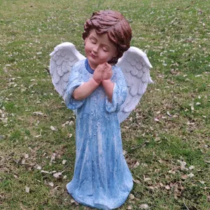 Close-up detail of a charming praying angel garden statue with blue dress and white wings.