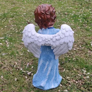 Detail shot of a resin angel garden statue with white wings, back view outdoor decor.