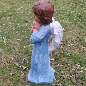 Detailed side view of an outdoor resin angel garden statue with white wings and blue dress.