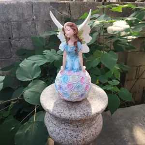 Outdoor resin angel flower fairy figurine detail shot with colorful rose sphere decoration.
