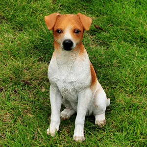 Detailed view of a cute resin dog figurine sitting on green grass for garden decoration.