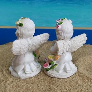 Gros plan détaillé de deux figurines d'anges en résine avec des couronnes sur le sable.