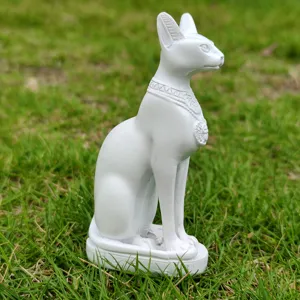 White Egyptian Bastet cat goddess resin statue ornament close-up shot on green grass.