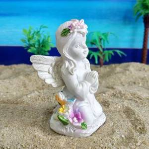 Détail de la figurine d'ange en résine montrant la posture de prière, la couronne et les fleurs.