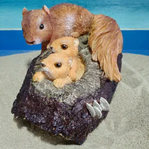 Close-up of cute resin squirrel sculpture in hollow tree for garden decor display.