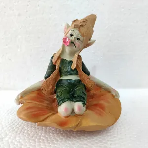 Close-up detail of the resin goblin fairy figurine sitting on flower base with cute expression.