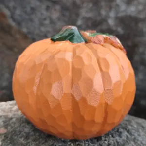 Resin carved pumpkin decor, detailed texture with green stem and leaf, close-up autumn ornament.