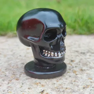 Black carved skull figurine ornament with round base, perfect for Halloween party decoration.