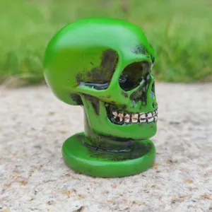 Green skull figurine close-up detail, resin skeleton head prop for Halloween decoration.