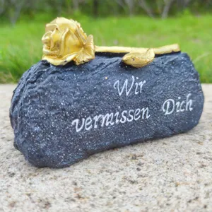 Memorial grave marker stone with golden rose decoration for mourning deceased loved ones.